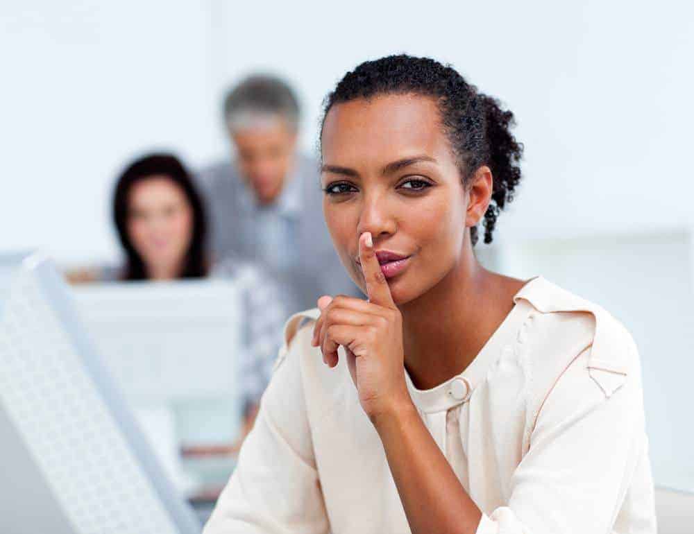 Black female with her pointer finger over her mouth asking people to quiet down. 