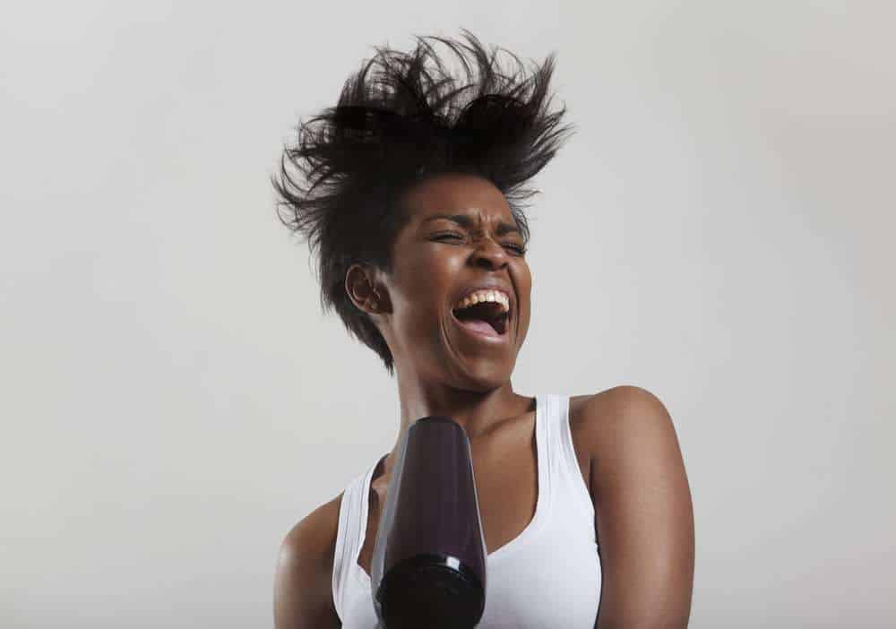 beautiful black women laughing while using a blow dryer