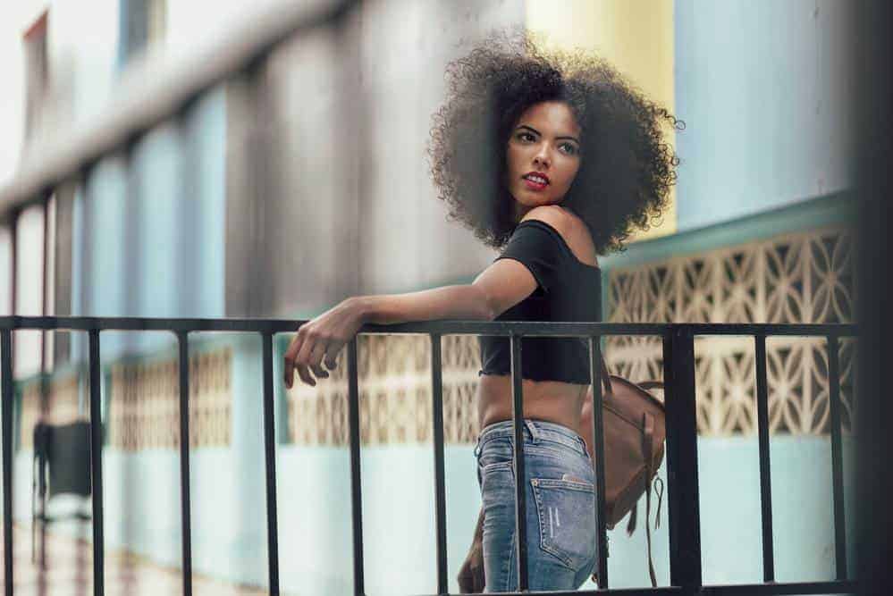 Cute African American female with fine hair after applying argan oil to her healthy hair strands.