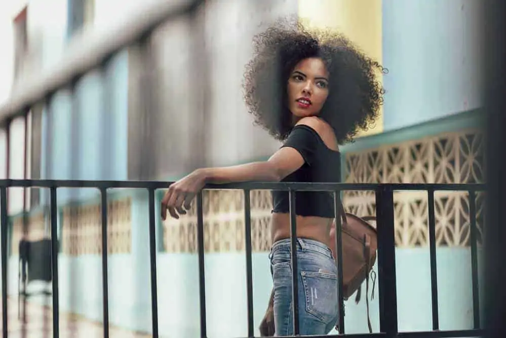 Learn How to Use Argan Oil for Hair Care (and Why It's Called Liquid Gold) 1 Cute African American female with fine hair after applying argan oil to her healthy hair strands.