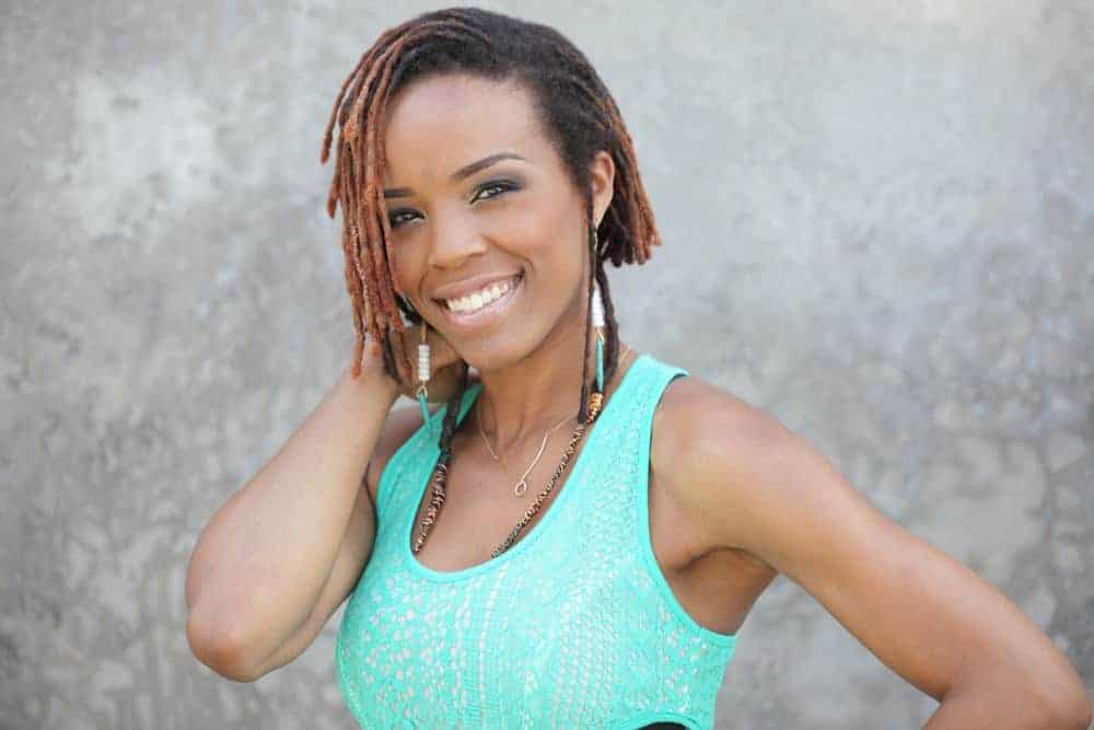 A young African American female wearing short faux locs (sometimes called fo locs or fake locs) with dark brown tips.