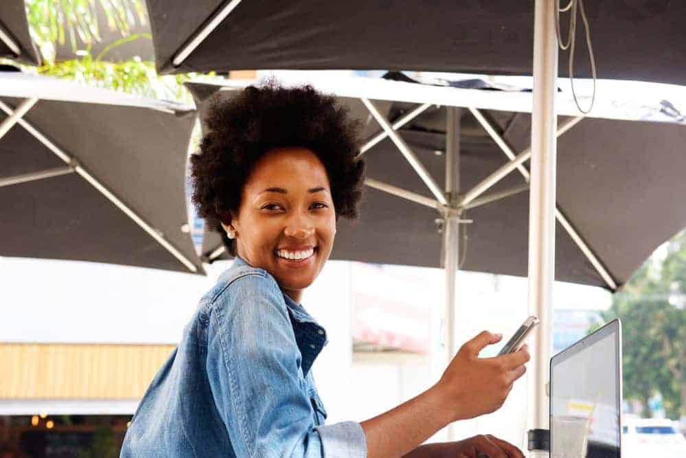 A black girl uses her mobile phone to read about the process of big chopping.