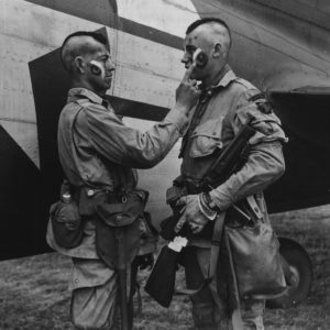 Paratrooper wearing mohawk hairstyle applies war paint