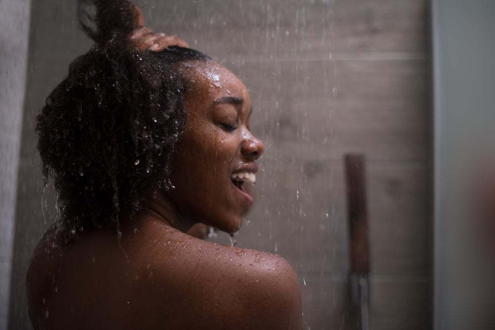Female washing her hair in the shower with argan oils, coconut milk, and Curl Right Shampoo