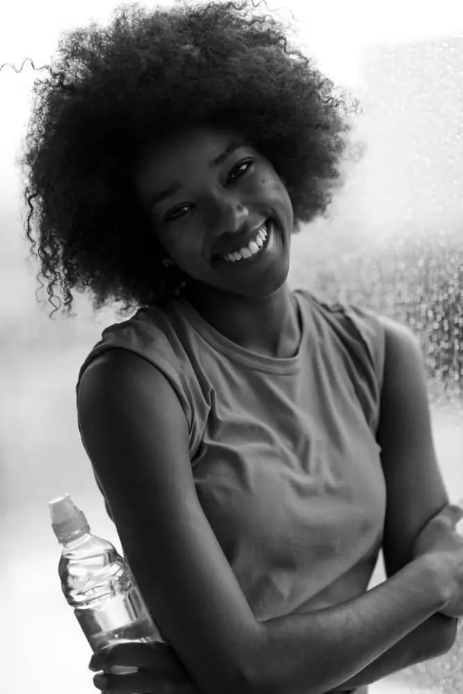 How to Pre-Poo Curly Hair With Olive, Coconut Oil, and More 5 Black girl posting for a photo after styling her hair with a hot oil treatment.
