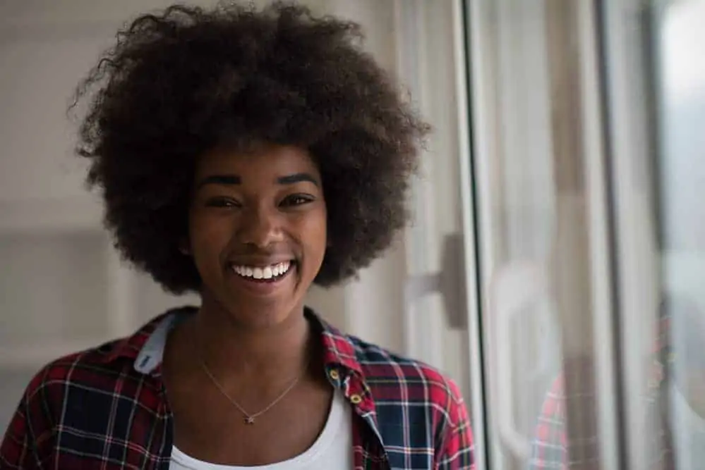 How to Pre-Poo Curly Hair With Olive, Coconut Oil, and More 3 A black girl after using a pre-poo overnight and a deep conditioner to treat her brittle hair strands.