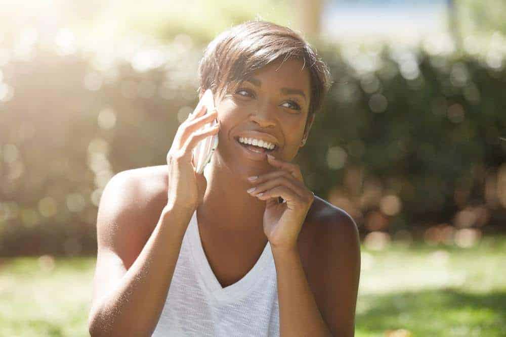 Black women using a mobile phone that has used heat training tactics for sensitive hair