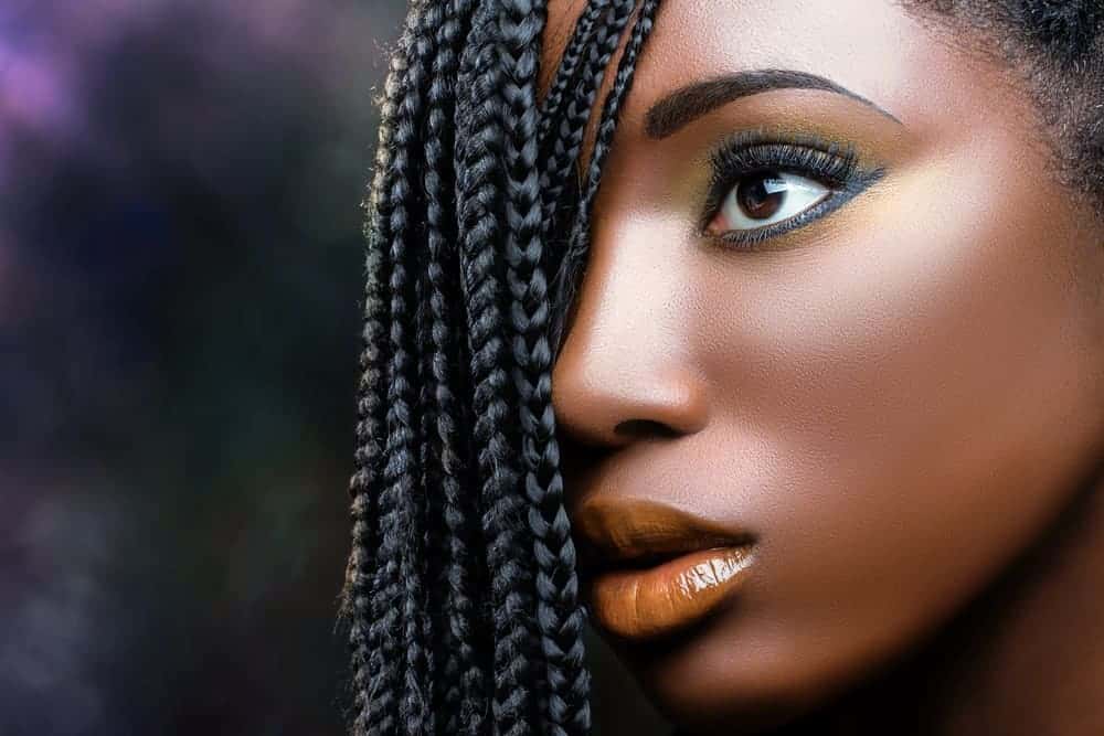 African American female wearing make-up with her eyes wide-open looking away from the camera.