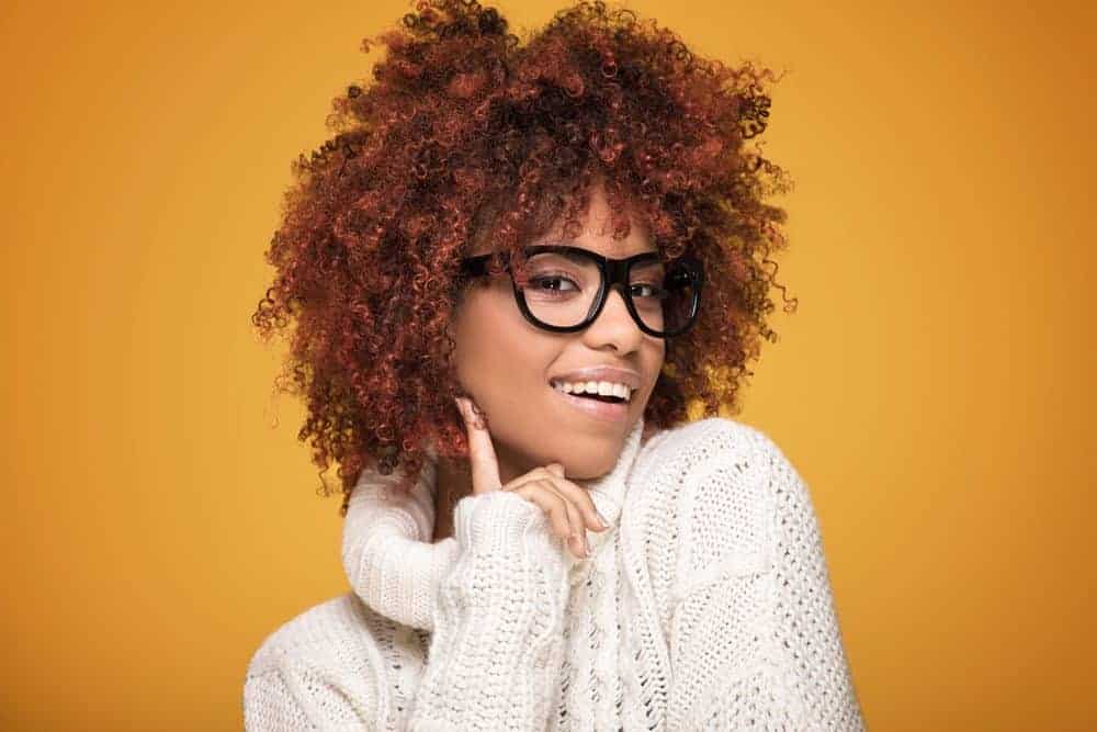 Female with curly hair looking directly into the camera on a yellow background.