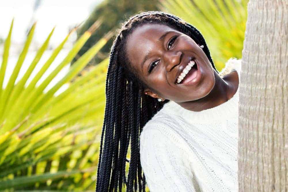 A dark-skinned black girl wearing medium-sized twists installed with Marley hair creating long locks on a 4B hair type.