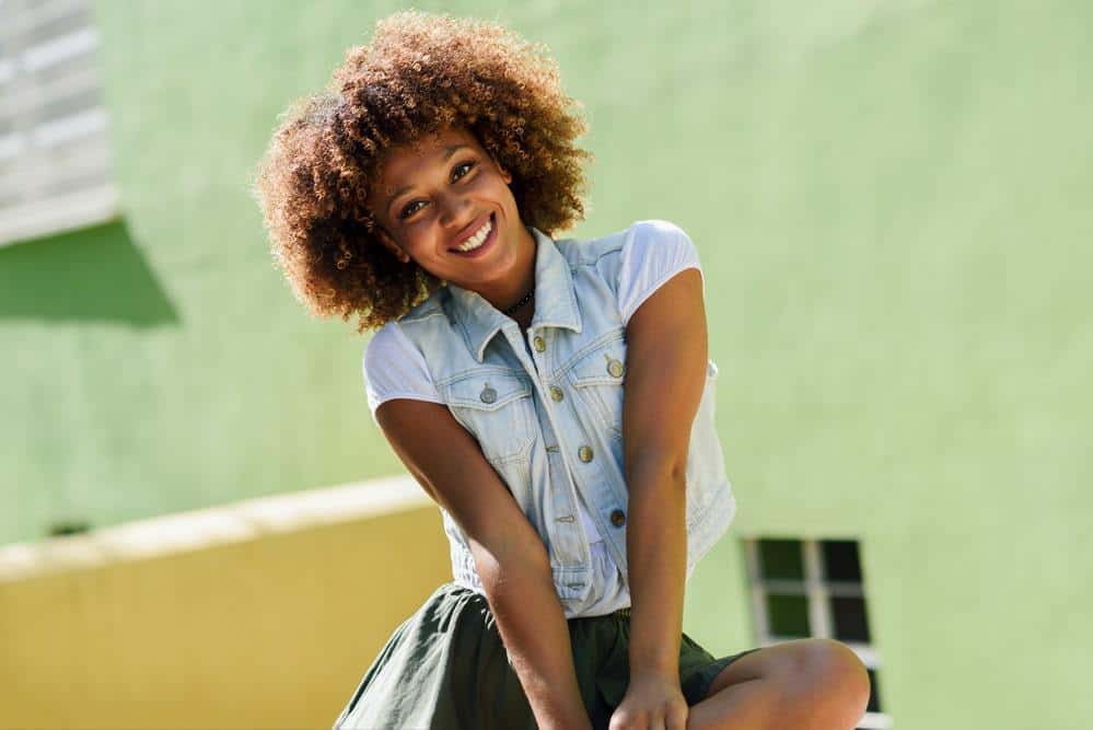 African American female with damaged hair strands from excess use of blow dryers and a daily washing routine.