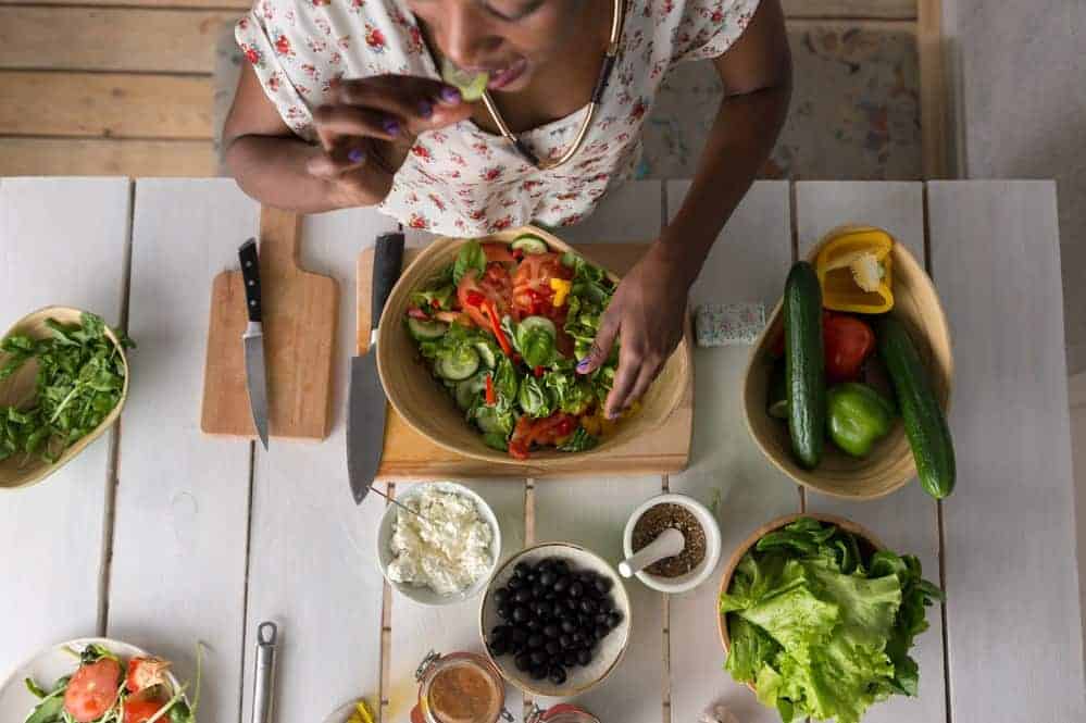 This young African American female is making a salad, which is a great food for hair growth and thickness.