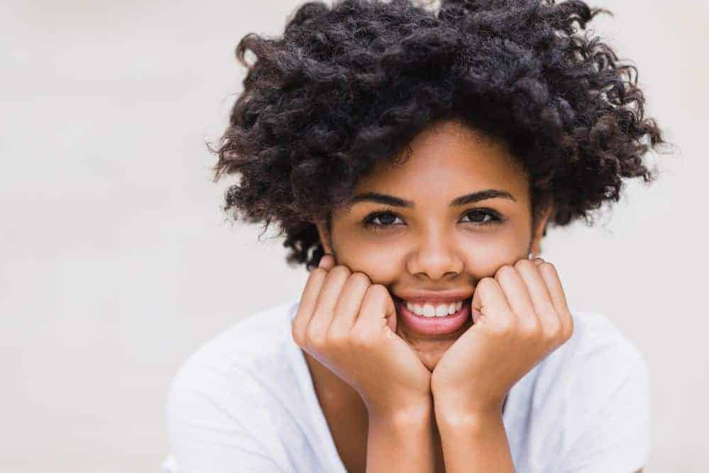 Cute black woman showing off her naturally curly hair with a big smile