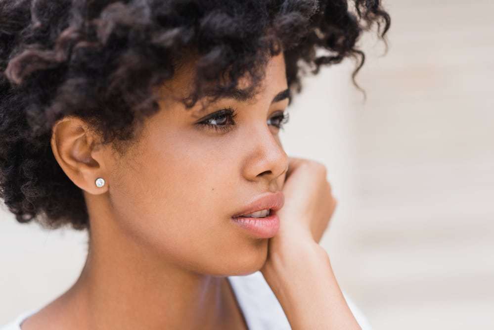 Young black girl considering washing hair with a few drops of diluted apple cider vinegar