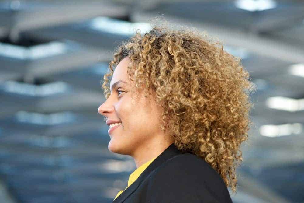 A cute black lady with a curly hairstyle after using avocado oil as a hair mask on her damaged hair.