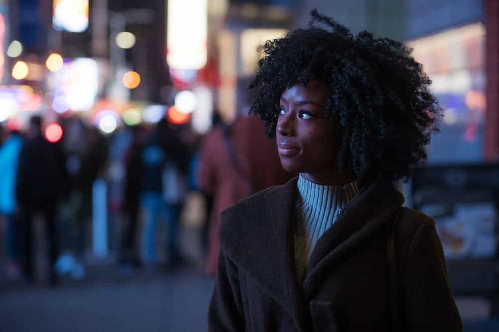 Belle donne nere con i capelli ricci che camminano attraverso una strada cittadina di notte.
