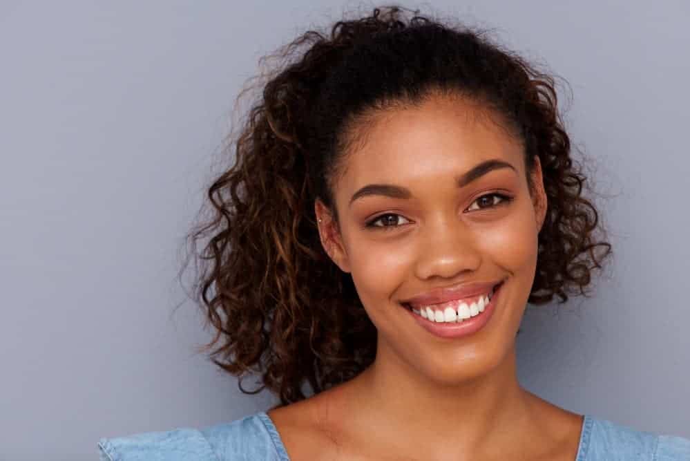 A light-skinned black girl with fragile edges styled her wispy baby hairs with curly girl-approved hair treatments.