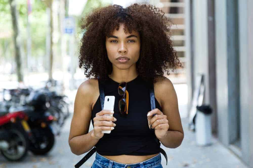 A black girl that uses grapeseed hair oil within her hair regimen to promote hair growth and prevent scalp dryness.