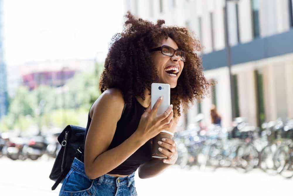 A young African American female walking on the street of downtown Birmingham, Alabama, wearing casual clothes.