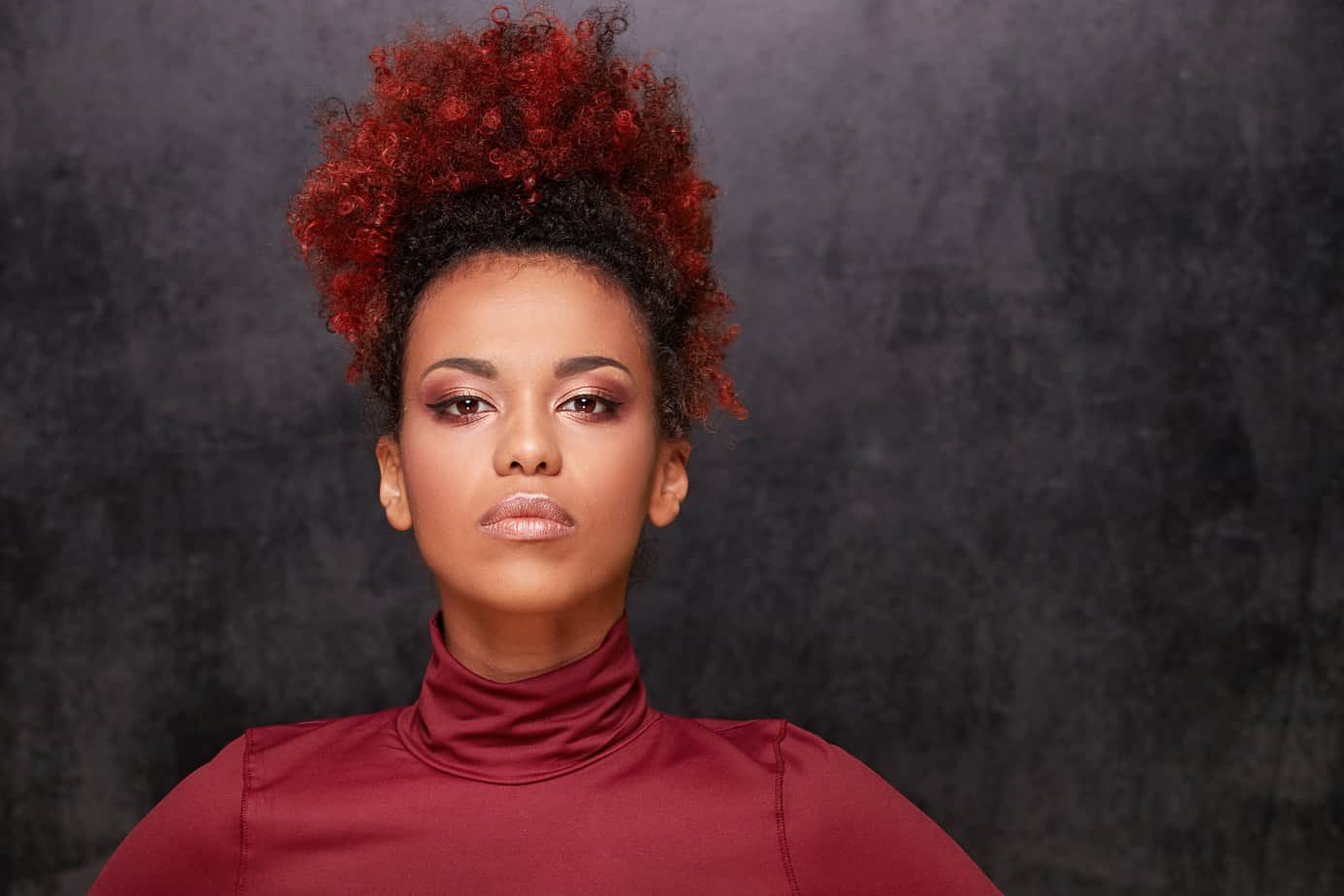  Lindas mujeres afroamericanas con cabello rizado rojo preguntando a un colorista de cabello cuánto cuesta teñirse el cabello.