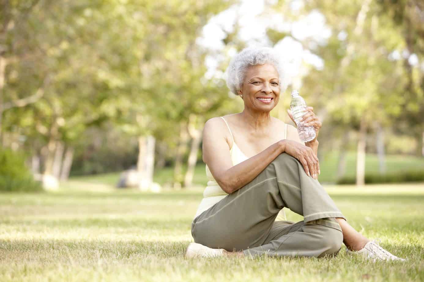 African American lady with curly gray hair sitting the park after a workout.