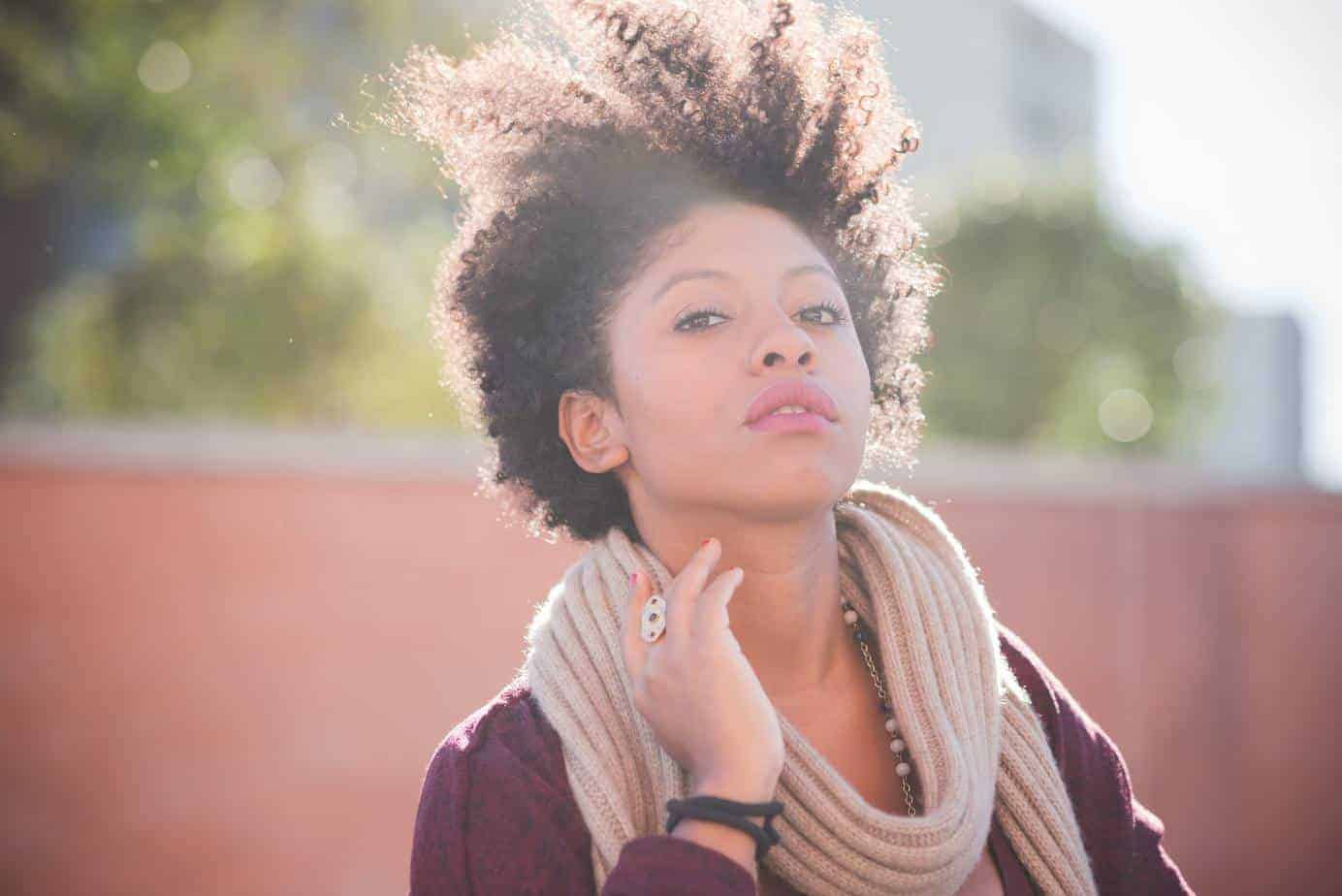 Cute black girl looking directly into the camera with curly hair and red lipstick.