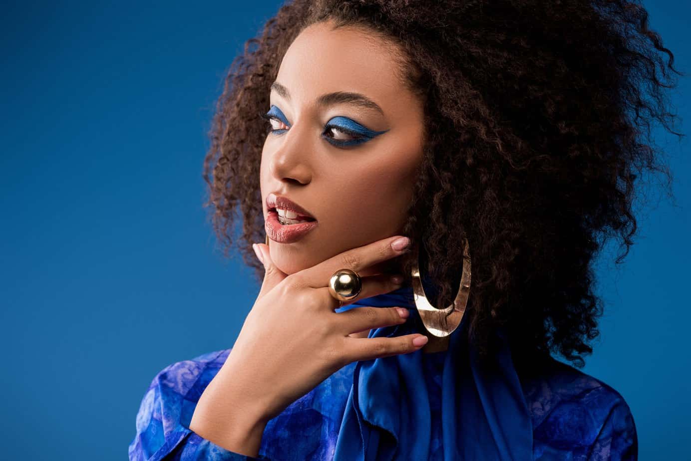 Beautiful African American wearing blue shirt, gold ear rings, and make-up after using rosemary oil for hair growth