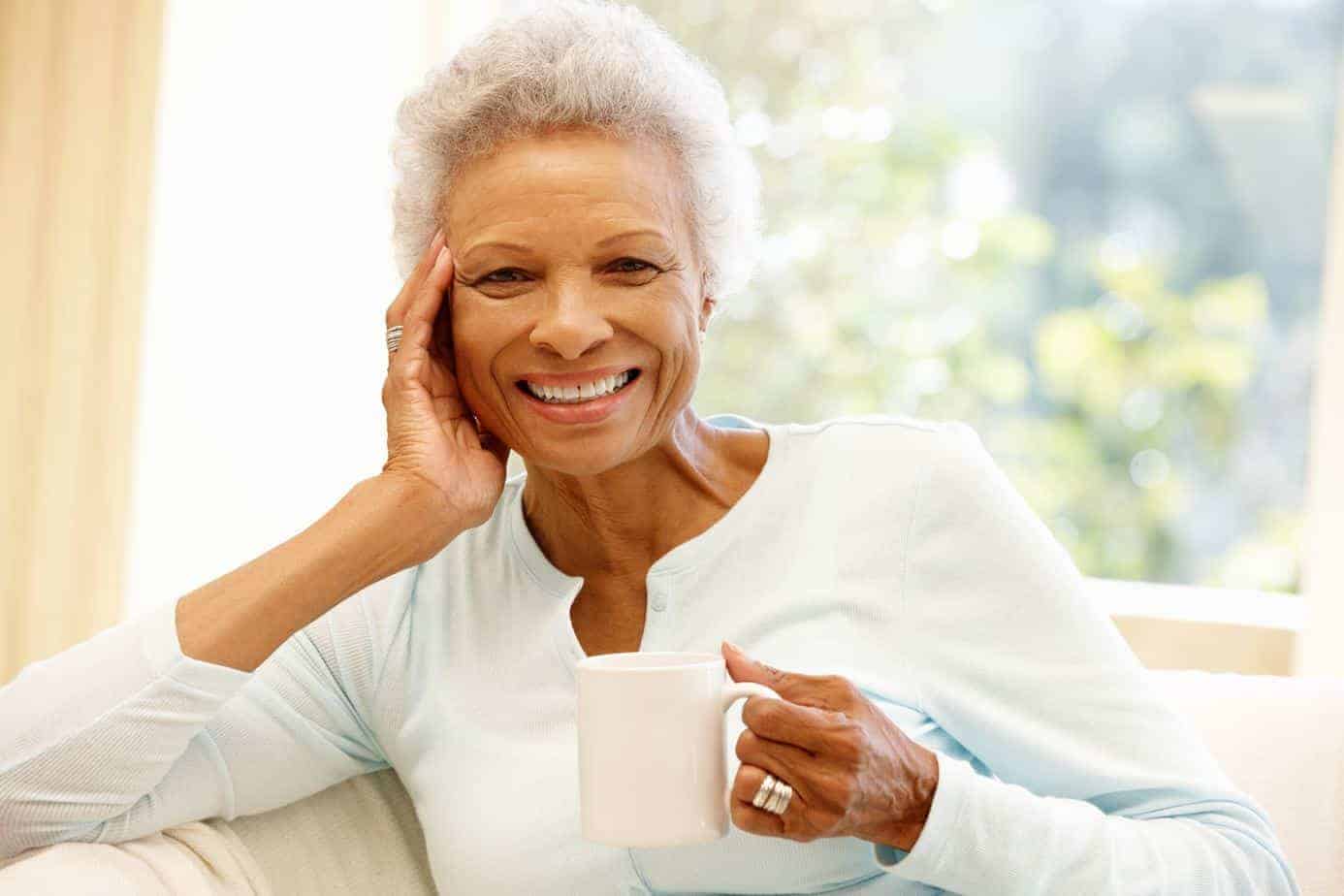 Elderly black women with gray hair drinking coffee