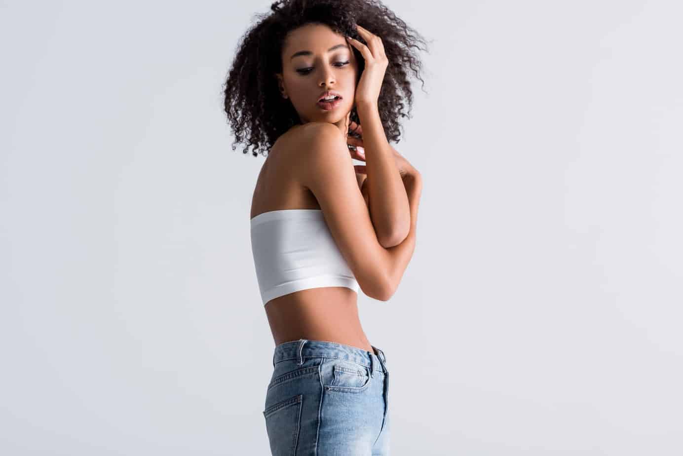The Best Way to Use Rosemary Oil for Hair Growth 2 cute skinny back girl wearing jeans and a white crop top while admiring her appearance