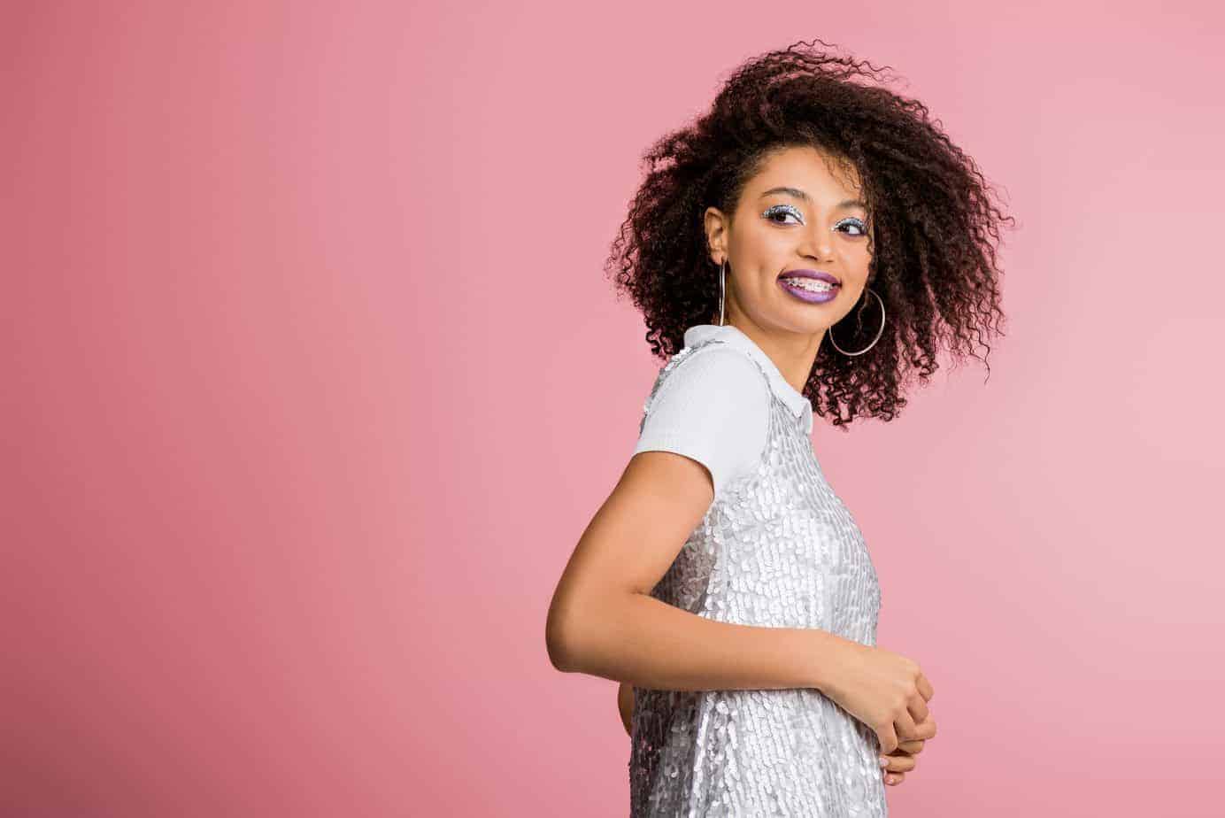The Best Way to Use Rosemary Oil for Hair Growth 9 female with curly hair wearing make-up looking back at the camera