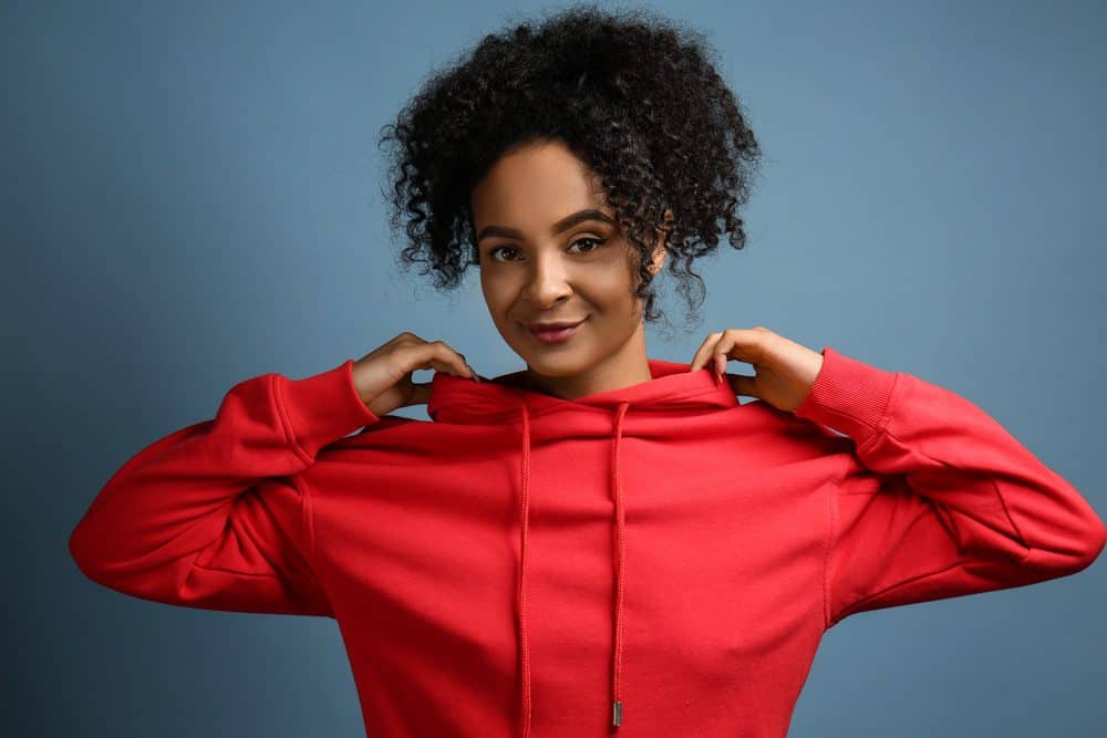 Beautiful African-American woman that moisturizes dry hair with water and coconut oil using a plastic spray bottle.