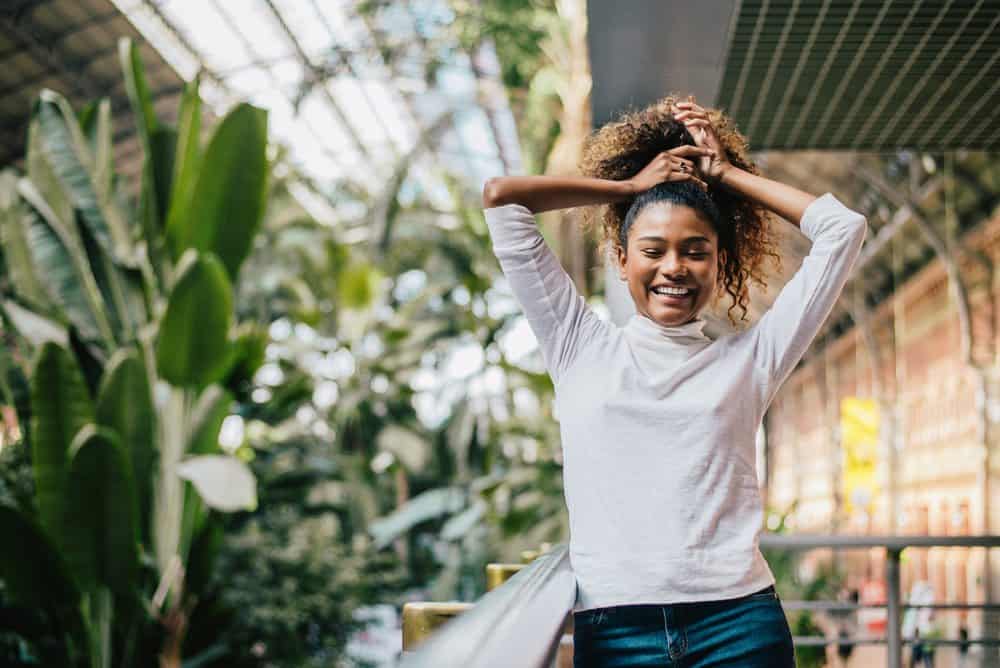 Young stylish woman holding her frizzy wavy hair that been treated with thyme oil for hair growth.