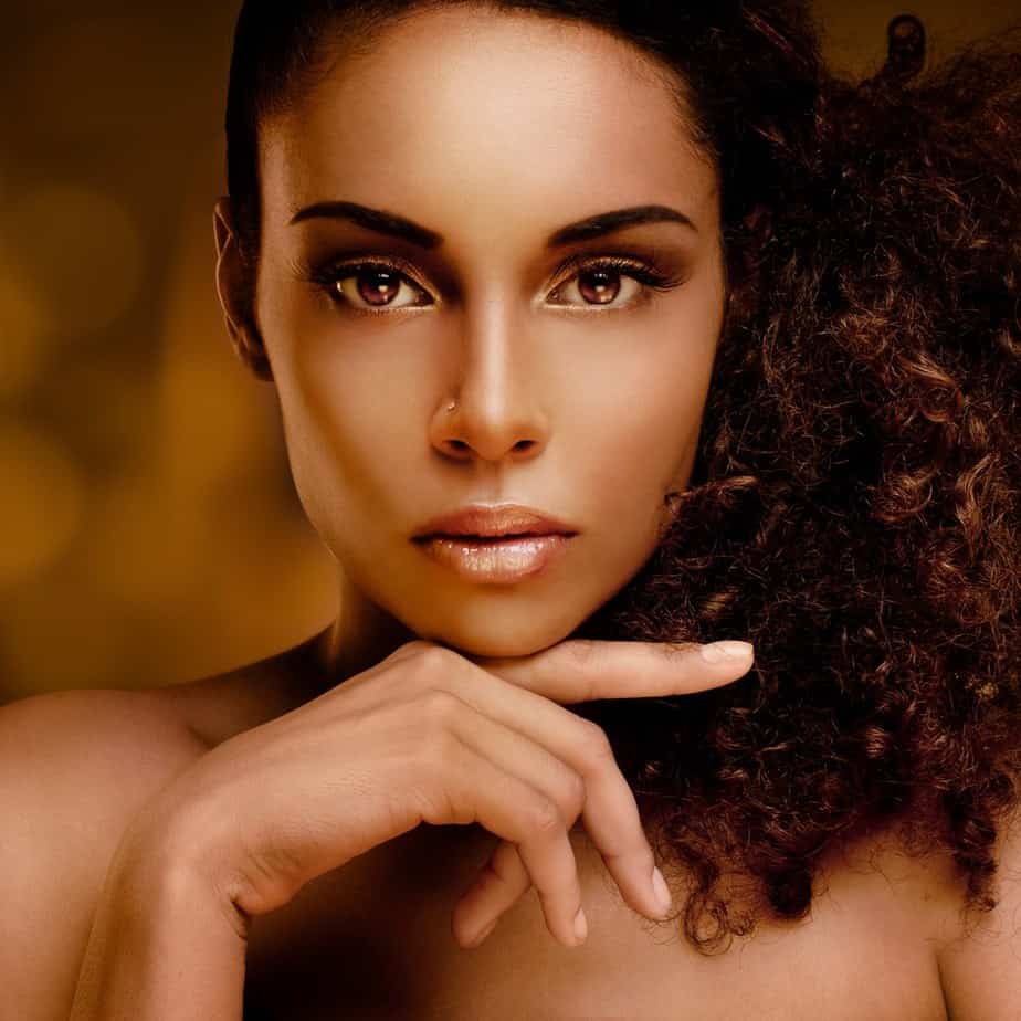 Portrait of a beautiful young African woman gently touching her face with a natural hairstyle.