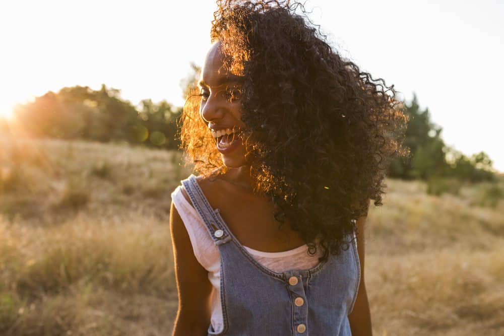 Women with clary sage oil treated hair smiling with pretty white teeth standing in the sun.