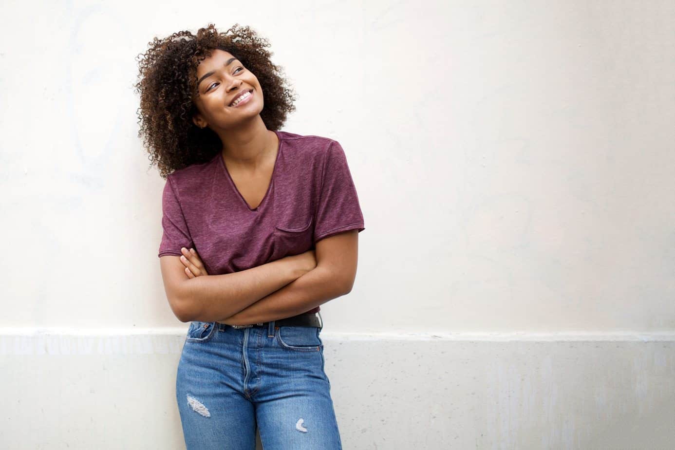 Cute black female with her arms crossed wearing a purple t-shirt and jeans