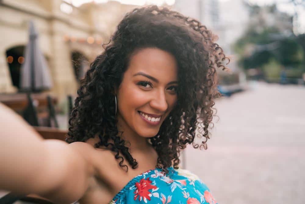 African American female with naturally curly hair strands styled with unrefined almond oil and other natural oils.