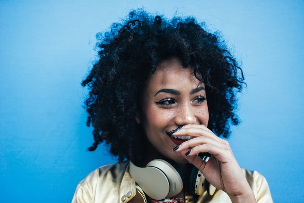 Beautiful Latin woman with curly hair looking away laughing at a joke.