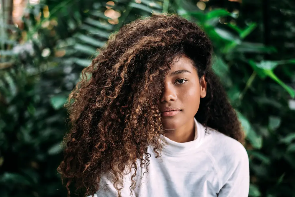 How to Use Thyme Oil for Hair Growth, Stress, Dry Scalp, and More 10 Beautiful dark skinned girl with curly hair.