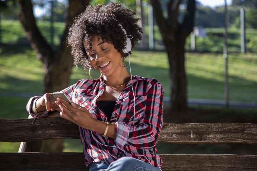 Young African American woman listening to music on cell phone.