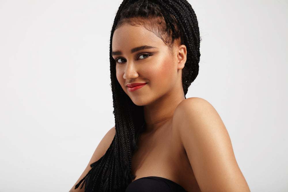 Happy pretty black woman with ideal skin wearing braids and red lipstick.