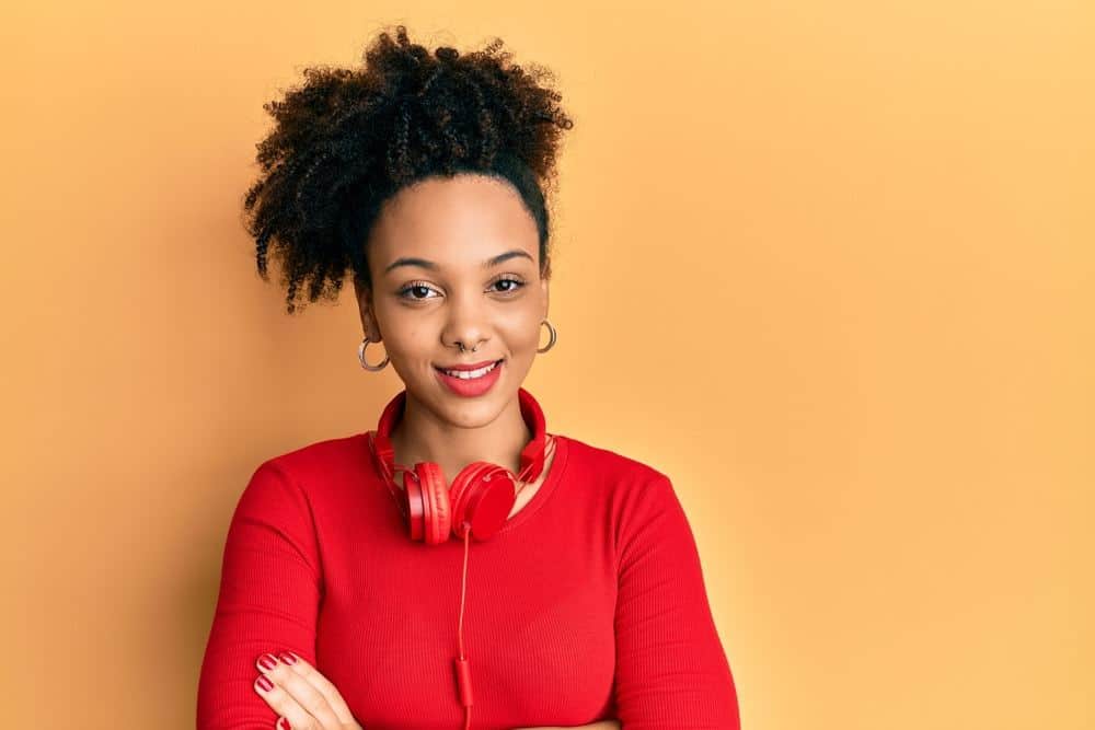 Young African American girl listening to music using headphones with a curly hairstyle that been treated with peppermint oil.