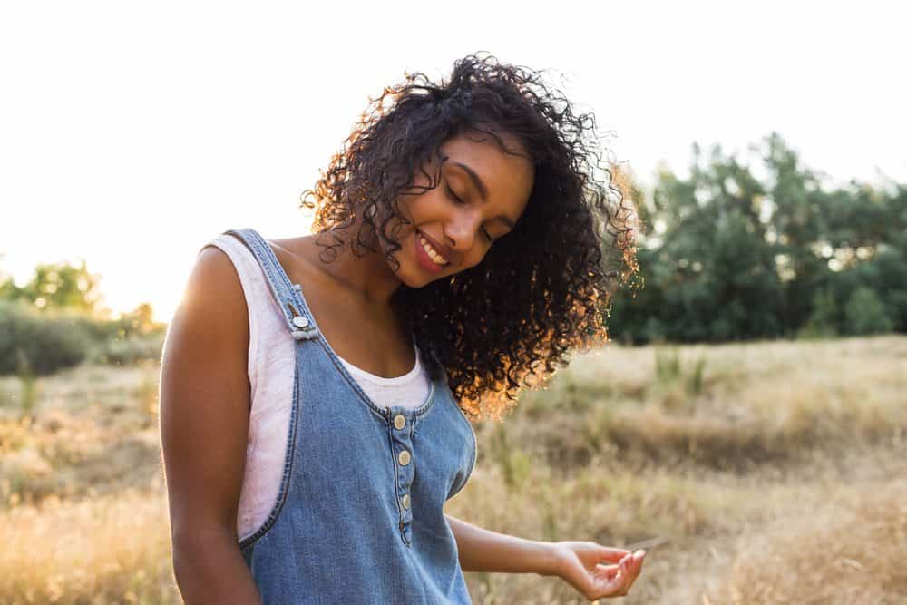 Cute women with clary sage oil hair admiring how beautiful her hair looks outside.