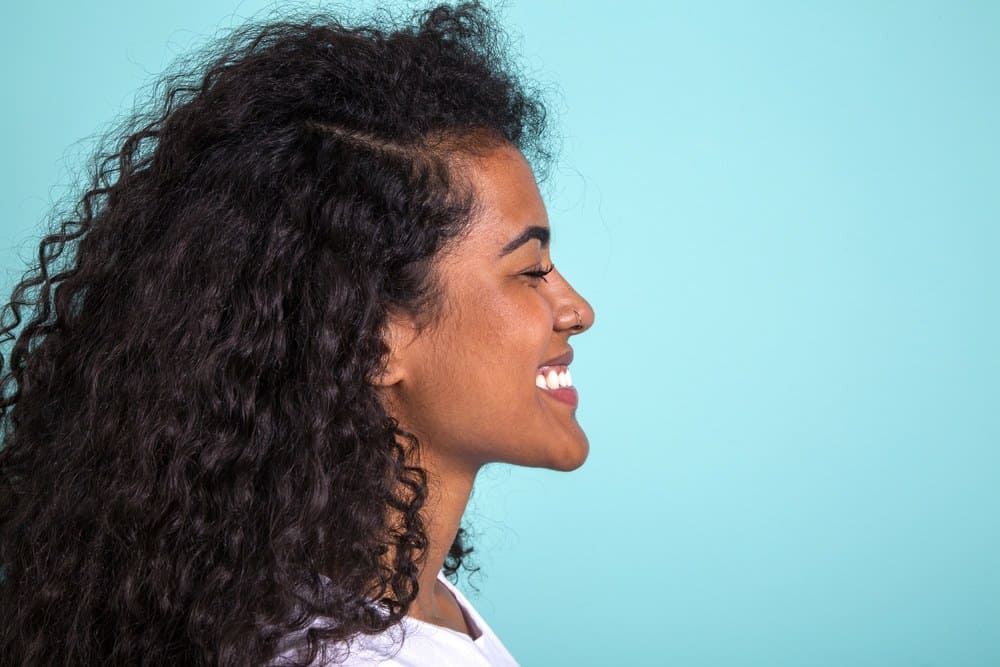 Side view of a pretty Indian American woman with naturally curly wavy type 3a hair type.