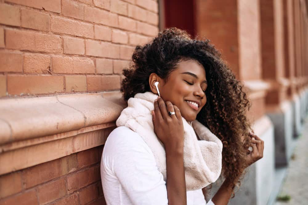 Portrait of young attractive black girl in urban background listening to the music with headphones.