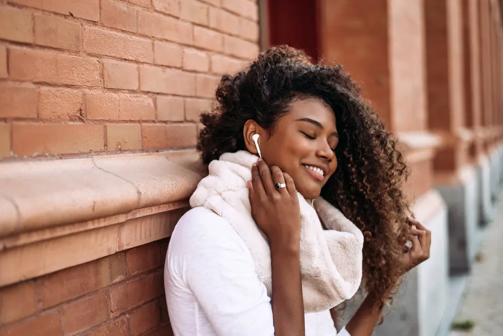 How to Use Thyme Oil for Hair Growth, Stress, Dry Scalp, and More 11 Portrait of young attractive black girl in urban background listening to the music with headphones.