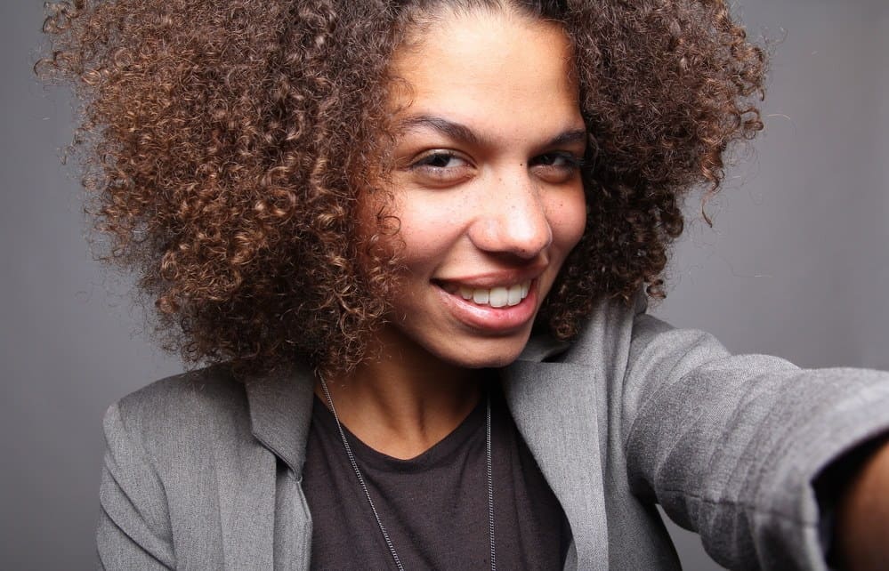 African American business women with curly hair wearing a gray business suit and black shirt.