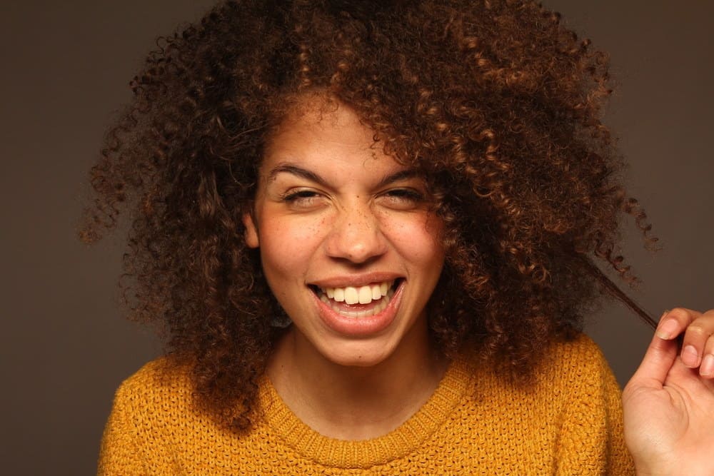 Cute African American female with curly hair follicles styled with a few drops of rosemary essential oil.