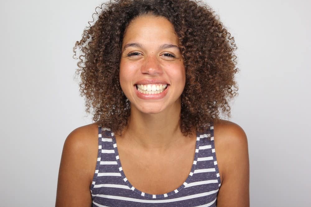Mixed race female wearing a blue and white shirt with wavy hair that's been treated with safflower oil.
