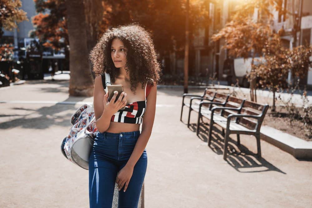 Indian female with arnica oil in her bag with type 3a naturally curly hair walking outside in Atlanta Georgia. 