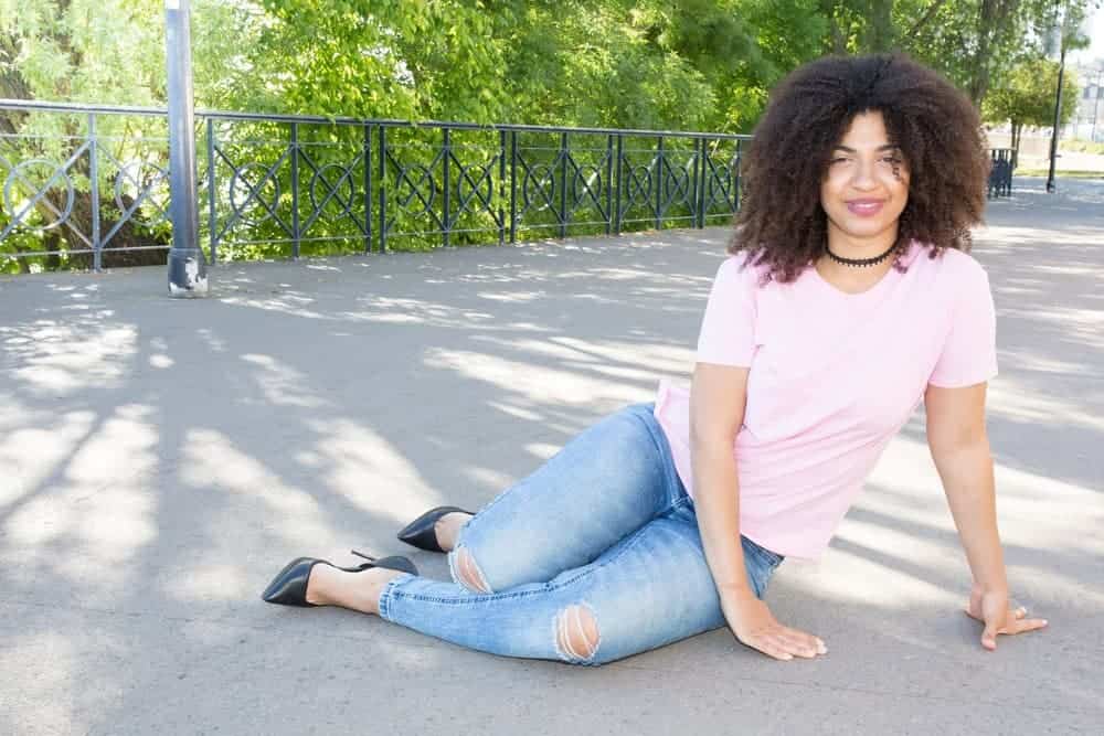 Cheerful African American girl with naturally curly hair sitting on the ground in the city center in Birmingham, Alabama.